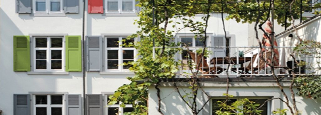 Eine Dachterasse von einem Mehrfamilienhaus mit einem Baum davor